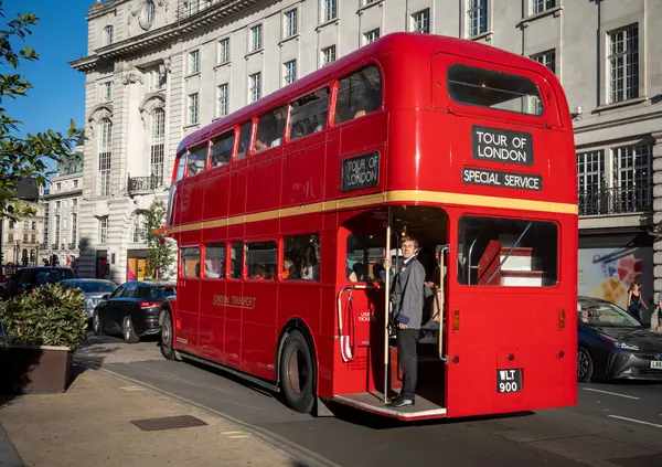 Geleneksel kırmızı bir Routemaster Londra otobüsü ve Londra turları için kondüktör kullanılıyor. Londra, İngiltere, İngiltere