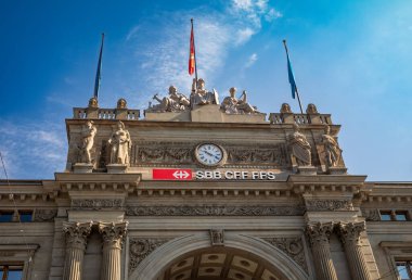 The historic neo-Renaissance facade of Zurich HB, one of Switzerland's most iconic train stations with its archway, ornate stonework and clock. clipart