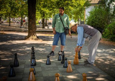 İki adam, İsviçre 'nin Zürih kentindeki eski Roma kalesinin bulunduğu tepedeki Lindenhof parkında satranç oynuyor..