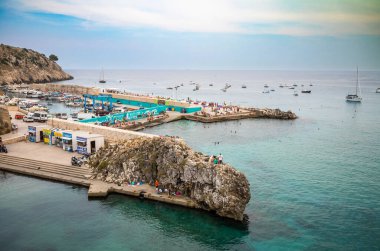 Kayalıklarda dinlenen ve dalgakıran boyunca Castro Marina, Apulia, İtalya 'yı koruyan insanlara bakıyorum..