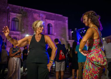 İnsanlar, İtalya 'nın Apulia eyaletinin Alessano kentinde Canzoniere Grecanico Salentino veya CGS' nin verdiği bir konserde Pizzica dansını seviyorlar. Grup geleneksel pizza ya da Salento halk müziği icra eder..