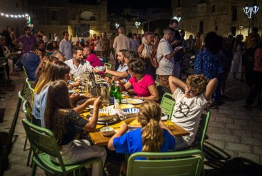 Pizzica folk müzik grubu Canzoniere Grecanico Salentino ya da CGS, Alessano, Lecce County, Apulia, İtalya 'da çalarken bir aile kasaba meydanında akşam yemeği yer. Pizzica ya da Tarantula, Salento folk müziğinin bir türüdür..