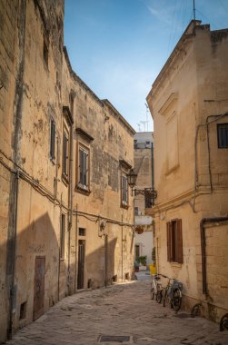 İtalya 'nın antik Lecce kentindeki taş binalarla çevrili küçük bir avluda bir duvara karşı iki bisiklet..