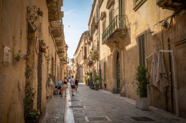 İtalya 'nın antik Lecce, Apulia kentinin göbeğinde taş binalarla dolu dar bir sokakta bir grup turist..