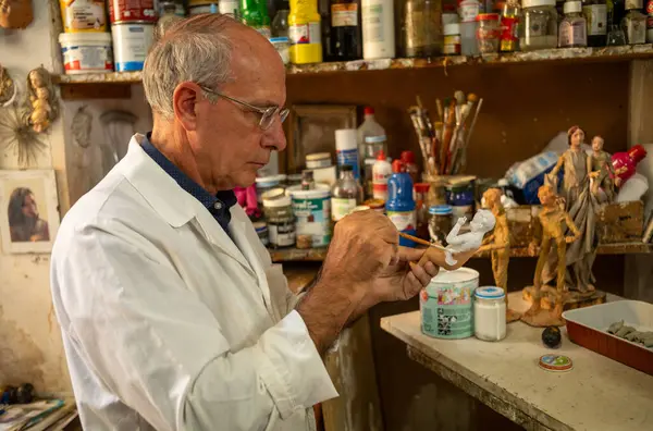 Bir cargoestai, ya da dini eserler zanaatkarı, İtalya 'nın antik Lecce kentindeki atölyesinde küçük bir melek figürü resmediyor. Cargoestai, dini figürler ve geçit törenleri ve kilise dekorasyonları sanatında uzmanlaşmıştır..