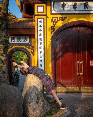 Batı Gölü, Hanoi, Vietnam 'daki antik Tran Quoc Pagoda' nın dışında sabah egzersizleri yaptığı gibi bir adam bir kayanın üzerinde geriye doğru eğilir..