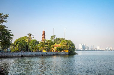 Batı Gölü 'ndeki antik Tran Quoc Pagoda Hanoi, Vietnam' daki modern yüksek binalarla. Pagoda tarihi 6. yüzyıla dayanır ve stupa 1998 yılında inşa edilmiştir..