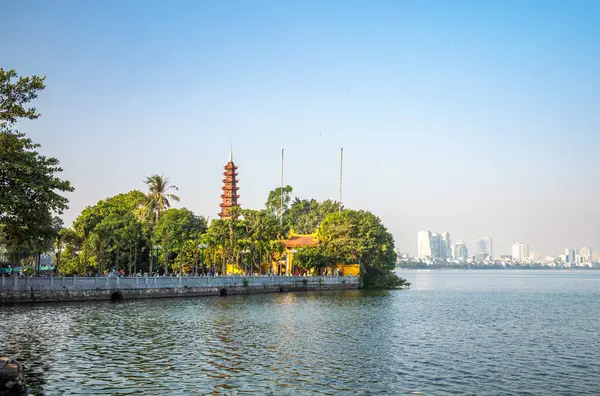 Batı Gölü 'ndeki antik Tran Quoc Pagoda Hanoi, Vietnam' daki modern yüksek binalarla. Pagoda tarihi 6. yüzyıla dayanır ve stupa 1998 yılında inşa edilmiştir..