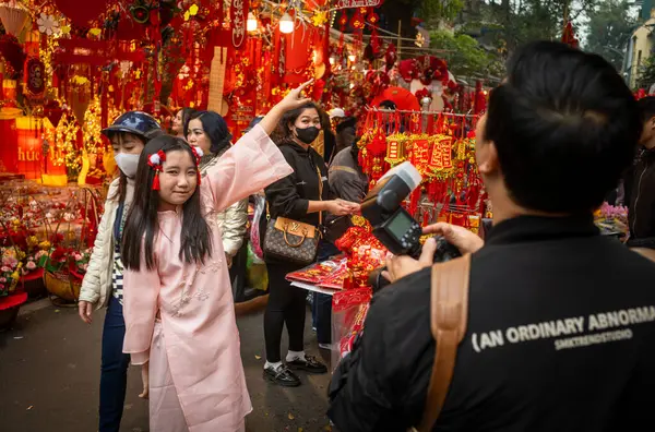 Geleneksel pembe ao dai kostümü giymiş genç bir kız Tet 'te ya da Hang Ma, Hanoi, Vietnam' daki yeni yıl pazarında fotoğraf için poz veriyor..