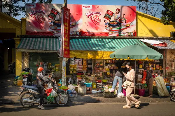 Dükkanın önünde alışveriş yapanlar Chau Long Market, Hanoi, Vietnam 'da yiyecek ve market malzemeleri satıyorlar..