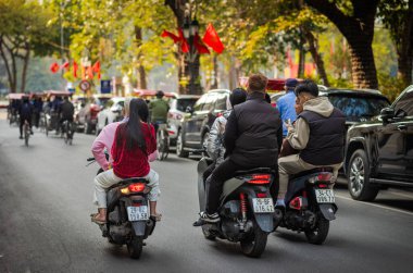 Üç motosikletli ve kask takmayan bir grup Vietnamlı genç arkadaş Hanoi, Vietnam 'ın merkezindeki Hoan Kien Gölü yakınlarındaki bir yolda seyahat ediyorlar..