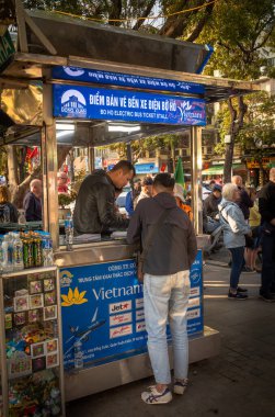 Vietnamlı bir adam, orta Hanoi, Vietnam 'daki Hoan Kiem Gölü' nün yanındaki turistik otobüs gezisi için bilet alıyor.