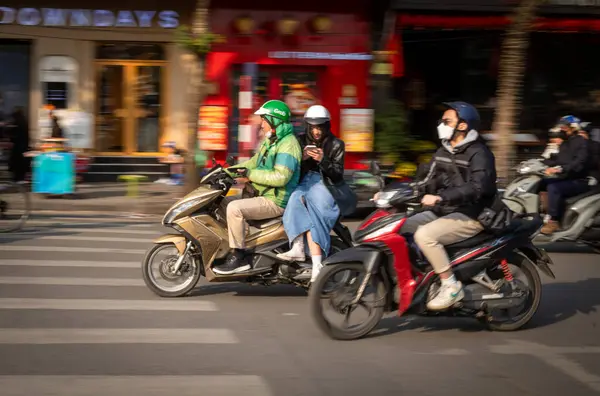 Vietnamlı genç bir kadın cep telefonuna bakar. Vietnam 'ın göbeğindeki Hoan Kiem Gölü' nün yanında bir motosiklet taksisinin arkasında yan tarafındaki eyere biner.