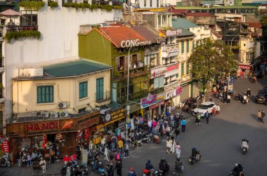 Hanoi, Vietnam 'ın merkezindeki Dong Kinh Nghia Thuc Meydanı' nın yanındaki dükkanlara ve kafelere tepeden bakan insanlar ve motosikletler.