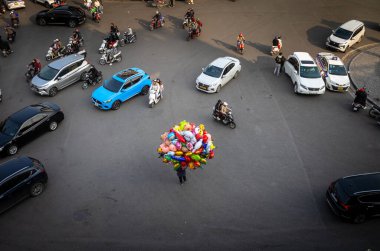 Hayvanlar şeklinde balonları dolduran bir helyum satıcısı, Tet 'in yeni yılı, Hanoi, Vietnam' da trafiğin ortasında duruyor..