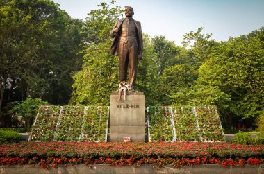 Genç bir çocuk, Lenin Park, Hanoi, Vietnam 'da Vladimir Lenin' in dev bronz heykelinin altındaki taş kaidede oturuyor. Heykel 1980 yılında Lenin 'in 110. doğum gününü anmak için dikildi..