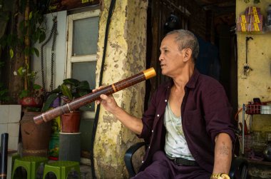 Yeşil çay satan bir sokak satıcısı geleneksel bambu su borusuyla güçlü tütün içiyor..