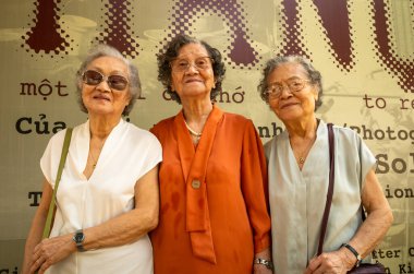 Üç yaşlı Vietnamlı kız kardeş Hanoi, Vietnam 'da bir fotoğraf sergisini ziyaret ediyor.