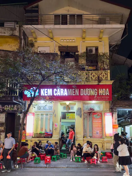İnsanlar geceleri Duong Ha 'da yiyorlar. Krem karamel, Hanoi, Vietnam üzerine uzmanlaşmış ünlü bir aile işletmesi..