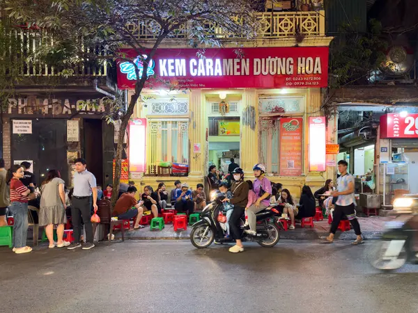 İnsanlar geceleri Duong Ha 'da yiyorlar. Krem karamel, Hanoi, Vietnam üzerine uzmanlaşmış ünlü bir aile işletmesi..