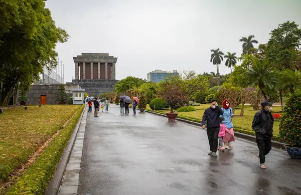 Vietnamlı aileler, devrimci kahraman Ho Chi Minh 'in mumyalanmış bedenini anıtmezarında ziyaret ettikten sonra kış boyunca yağmurda yürürler. Hanoi, Vietnam.