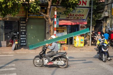 Bir adam motosikleti Cau Giay, Hanoi, Vietnam 'ı sürerken omuzunda uzun süre prefabrik plastik taşır.