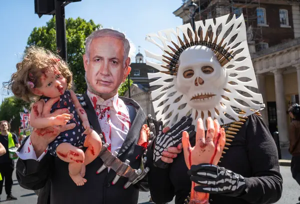 Filistinli protestocular Benjamin Netanyahu maskesi takıyor, kurşunlu bir kafatası maskesi, yaralı bir bebeği ve kesilmiş uzuvları tutuyor, Londra, İngiltere.