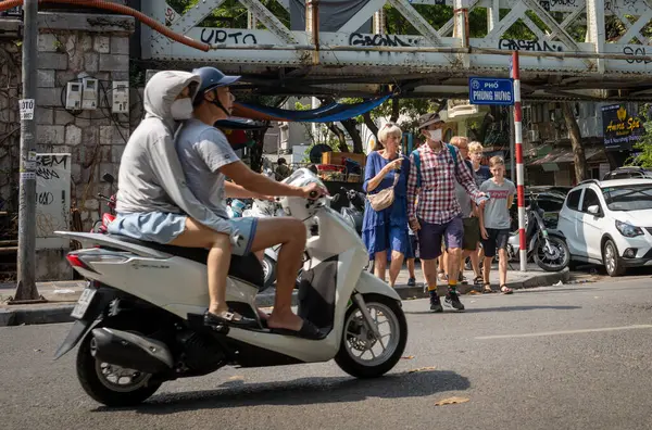 Yetişkin ve çocuklardan oluşan bir grup Batılı turist Hanoi, Vietnam 'ın merkezinde yoğun bir yoldan geçiyor..