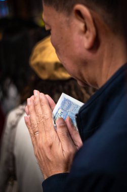 Bir Vietnamlı, Quan Thanh Tapınağı 'nda (veya Tran Vu Tapınağı) yeni yıl (Tet), Hanoi, Vietnam' da iyi şans için dua ederken 5000 dong tutar..