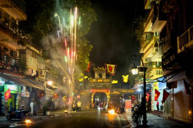 İnsanlar atalarına adak adadıkları adaklarını yakarken havai fişekler patlıyor. Ay 'ın yeni yılını müjdelemek için. Antik şehir kapısı O Quan Chuong, Hanoi, Vietnam' da..
