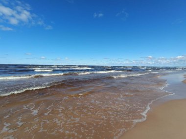 Bahar güneşli bir günde baltık denizi. Güzel deniz manzarası. Mavi bulutlar, parlayan dalgalar ve akan su. Doğa, resim gibi manzara, resim gibi manzara.