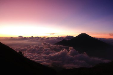 Güzel bir gün batımına karşı bir dağ silueti. Gökyüzü pembe ve mor renklerin karışımıdır. Huzurlu ve huzurlu bir atmosfer yaratır.