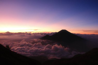 Güzel bir gün batımına karşı bir dağ silueti. Gökyüzü pembe ve mor renklerin karışımıdır. Huzurlu ve huzurlu bir atmosfer yaratır.