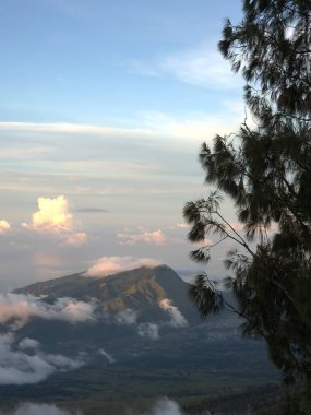 Uzakta bulutlu bir gökyüzü ile bir dağ sırası görülebilir. Bulutlar alçak ve yumuşaktır. Huzurlu ve huzurlu bir atmosfer yaratırlar.