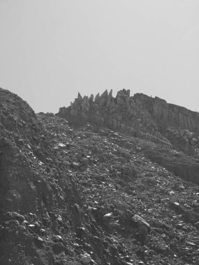 Kayalık yamaçlı bir dağ. Tepe kayalarla kaplı ve gökyüzü bulutlu.