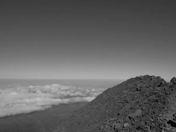 stock image A mountain top with a cloudy sky in the background. The sky is mostly clear with a few clouds scattered throughout