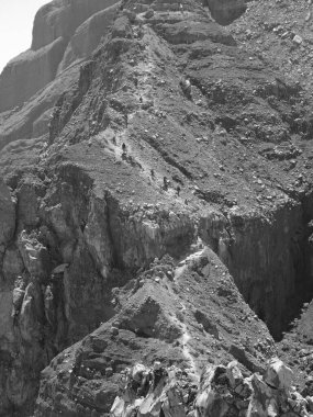 Önünde bir patika olan bir dağ. Yol kayalık ve dik. Dağ kayalar ve toprakla kaplı.