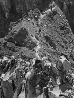 Önünde bir patika olan kayalık bir dağ. Yol kayalık ve sarp, ve yolda yürüyen birkaç insan var. Sahne maceralı ve zorlu, çünkü yolu takip etmek çok zor.