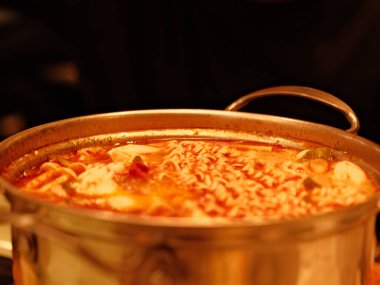 İçinde erişte ve et olan büyük bir tencere çorba. Çorba portakallı ve köpüklü.