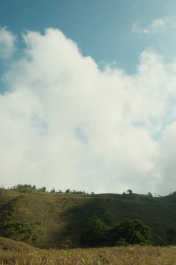 Arka planda dağ olan bulutlu bir gökyüzünün bulanık bir görüntüsü. Gökyüzü çoğunlukla bulutlu, birkaç mavi gökyüzü parçasıyla. Dağ uzakta.