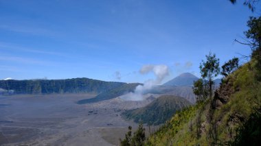 Uzakta volkan olan bir dağ sırası. Gökyüzü açık ve mavi