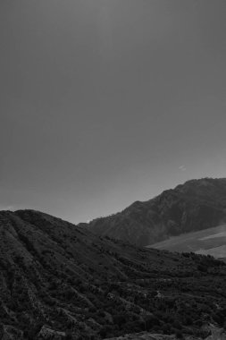 Açık mavi gökyüzü olan bir dağ sırası. Gökyüzü çok aydınlık ve dağlar çok karanlık.