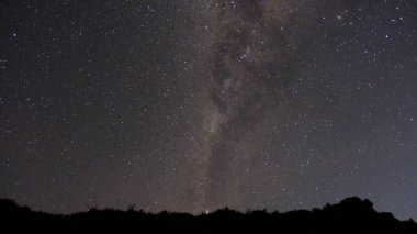 Gece gökyüzü yıldızlarla ve parlayan büyük bir süt bulutuyla dolu. Yıldızlar gökyüzüne dağılmış, bazıları birbirine daha yakın, bazıları ise daha da yayılmış.