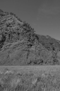 Önünde büyük bir tepe olan bir dağ sırası. Gökyüzü açık ve güneş parlıyor.