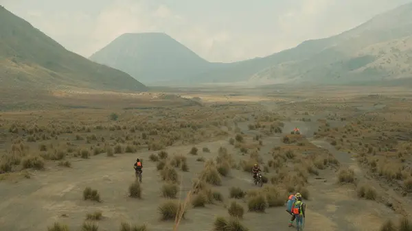 stock image A group of people are walking through a desert. The sky is cloudy and the sun is not visible