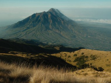 Uzakta bir şehir olan bir dağ sırası. Gökyüzü açık ve güneş parlıyor.