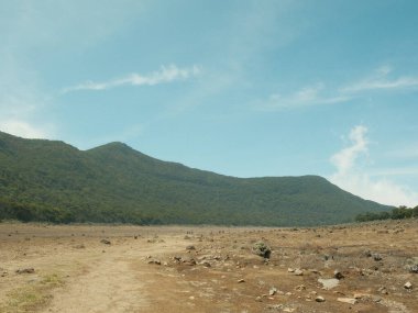 Arkasında dağ olan ıssız bir manzara. Gökyüzü açık ve mavi