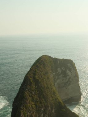 Okyanusa bakan kayalık bir uçurum. Su sakin ve gökyüzü bulutlu. Sahne huzurlu ve huzurlu.