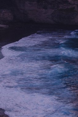 Dalgaların kıyıya çarptığı bulanık bir su kütlesi görüntüsü. Sahne sakin ve sakin, su durgun ve huzurlu görünüyor.