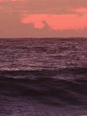 Okyanus sakin ve gökyüzü pembe. Su koyu mavi ve gökyüzü turuncu.